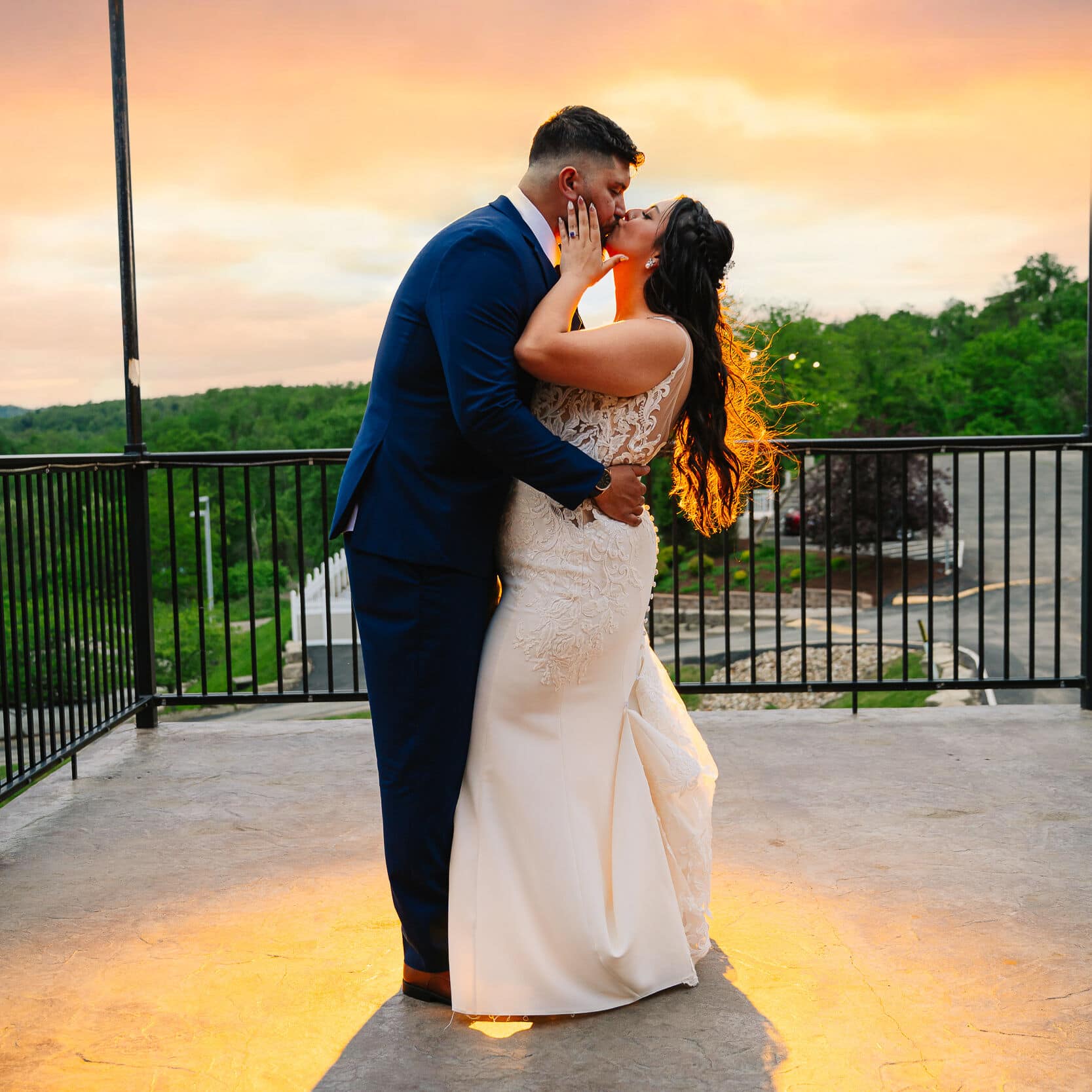 Bride and groom share a kiss at sunset on the terrace at The Sunset Room in Elizabeth, Pennsylvania.